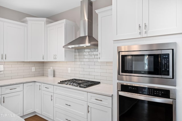 187 Tanners Cv, Johnson City, TN 37615 - kitchen with wall chimney exhaust hood, appliances with stainless steel finishes, white cabinetry, and decorative backsplash