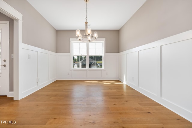 187 Tanners Cv, Johnson City, TN 37615 - unfurnished dining area with a chandelier, a decorative wall, wainscoting, and light wood-style flooring