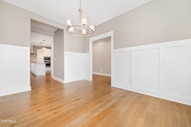 187 Tanners Cv, Johnson City, TN 37615 - empty room featuring a chandelier, a decorative wall, wainscoting, and light wood-type flooring