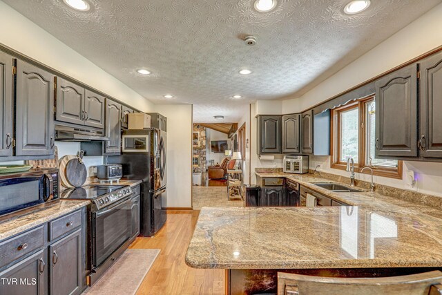 400 Heatherview Ct, Kingsport, TN 37663 - kitchen featuring range with electric cooktop, stainless steel microwave, under cabinet range hood, a textured ceiling, and a peninsula