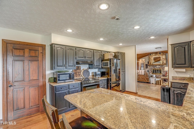 400 Heatherview Ct, Kingsport, TN 37663 - kitchen featuring range with electric stovetop, stainless steel microwave, under cabinet range hood, a textured ceiling, and a peninsula
