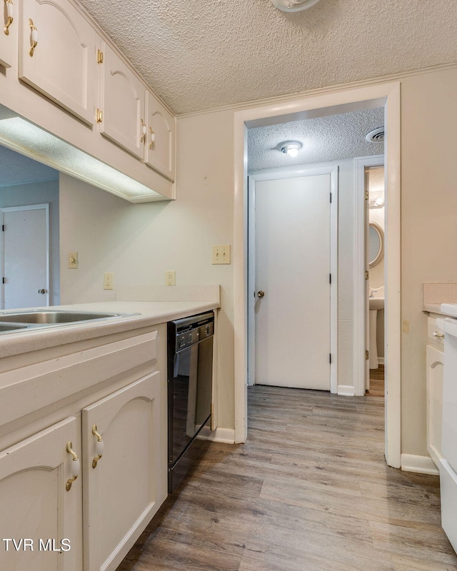 815 7th St Unit 815, Bristol, TN 37620 - kitchen with black dishwasher, a textured ceiling, light wood finished floors, light countertops, and white cabinets