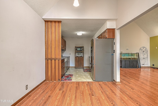 190 Sycamore Cir, Jonesborough, TN 37659 - kitchen featuring freestanding refrigerator, a textured ceiling, light wood-style floors, lofted ceiling, and brown cabinets