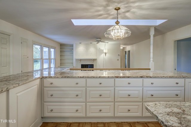 1710 Sundale Rd, Johnson City, TN 37604 - kitchen with ceiling fan, a skylight, a brick fireplace, a chandelier, and light stone countertops