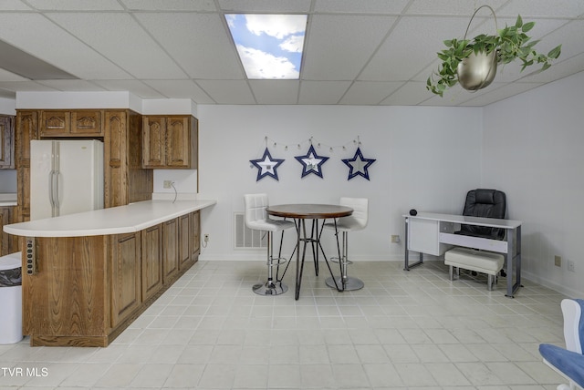 1710 Sundale Rd, Johnson City, TN 37604 - kitchen with freestanding refrigerator, light countertops, a peninsula, brown cabinetry, and a drop ceiling