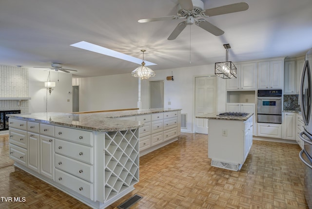 1710 Sundale Rd, Johnson City, TN 37604 - kitchen with a large island, appliances with stainless steel finishes, ceiling fan, a warming drawer, and white cabinets