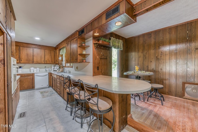 224 Meadow Dr, Bristol, TN 37620 - kitchen with dishwasher, brown cabinetry, a peninsula, light countertops, and wooden walls
