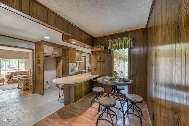 224 Meadow Dr, Bristol, TN 37620 - kitchen featuring wooden walls, healthy amount of natural light, white oven, light countertops, and crown molding