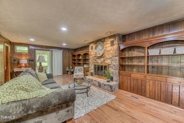 224 Meadow Dr, Bristol, TN 37620 - living area featuring wooden walls, a textured ceiling, wood finished floors, a stone fireplace, and recessed lighting