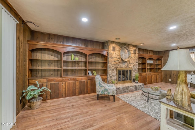 224 Meadow Dr, Bristol, TN 37620 - living area featuring wooden walls, wood finished floors, a textured ceiling, a stone fireplace, and built in shelves