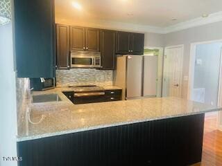 504 Amelia Ct, Blountville, TN 37617 - kitchen with stainless steel microwave, freestanding refrigerator, light stone countertops, tasteful backsplash, and ornamental molding
