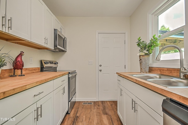 1010 Gibson Mill Rd, Kingsport, TN 37660 - kitchen featuring stainless steel appliances, butcher block counters, wood finished floors, and white cabinetry