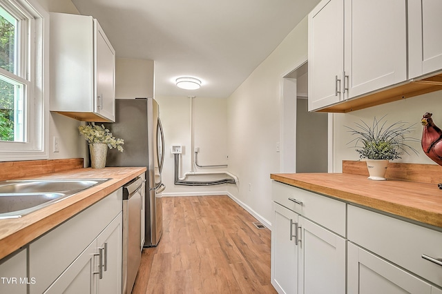 1010 Gibson Mill Rd, Kingsport, TN 37660 - kitchen featuring wooden counters, stainless steel dishwasher, light wood-style flooring, and white cabinets