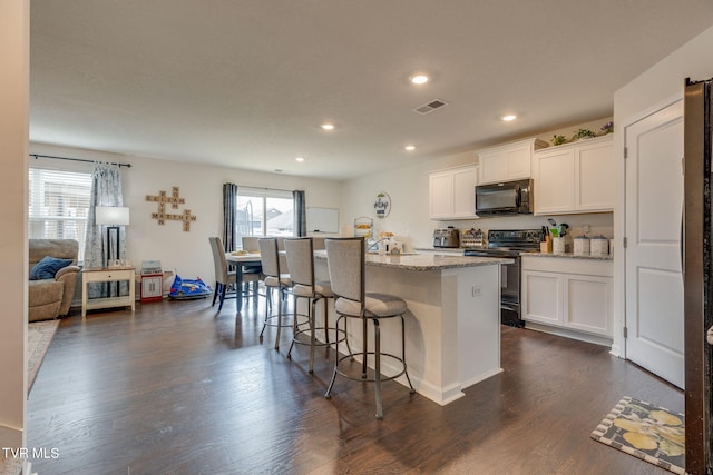 1233 Stamp Lodge Rd, Kingsport, TN 37660 - kitchen with black appliances, a kitchen bar, light stone counters, white cabinetry, and recessed lighting