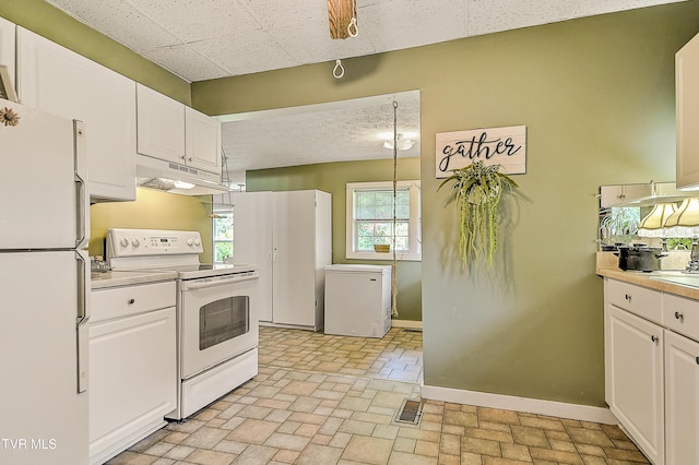 116 Esther St, Bristol, TN 37620 - kitchen with white appliances, under cabinet range hood, white cabinets, and brick patterned floors