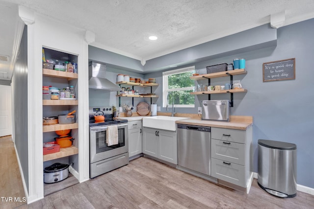 8202 Westland Dr, Knoxville, TN 37919 - kitchen featuring stainless steel appliances, wall chimney range hood, open shelves, a textured ceiling, and light wood-style flooring