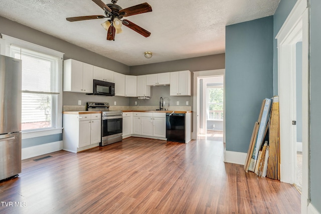 1234 E Center St, Kingsport, TN 37660 - kitchen with black appliances, light wood-style floors, white cabinets, ceiling fan, and a textured ceiling