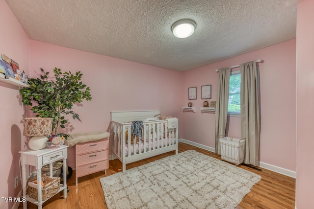 605 Dickerson St, Kingsport, TN 37665 - bedroom featuring a textured ceiling, light wood-style flooring, and a nursery area
