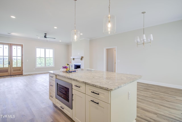 77 Sunset Rd, Johnson City, TN 37615 - kitchen featuring stainless steel microwave, light wood-type flooring, open floor plan, hanging light fixtures, and ornamental molding