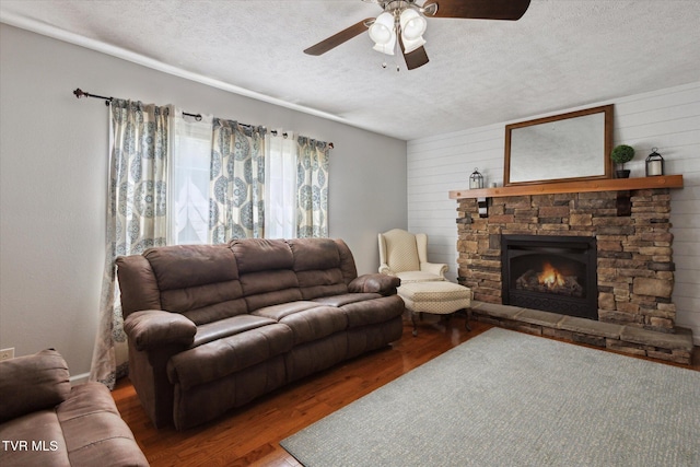 4404 Stillwood Ave, Kingsport, TN 37664 - living area with a textured ceiling, ceiling fan, wood finished floors, a stone fireplace, and wooden walls