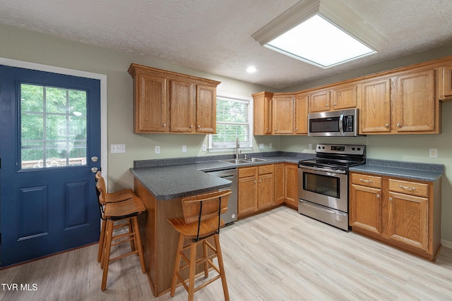 5630 Orebank Rd, Kingsport, TN 37664 - kitchen with appliances with stainless steel finishes, light wood-style floors, dark countertops, a peninsula, and brown cabinetry