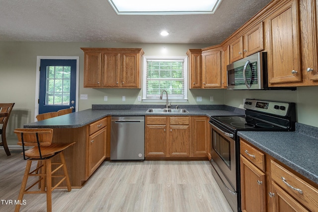 5630 Orebank Rd, Kingsport, TN 37664 - kitchen featuring stainless steel appliances, a peninsula, light wood-type flooring, brown cabinetry, and a textured ceiling