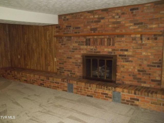 313 Milburn Ave, Kingsport, TN 37660 - unfurnished living room with carpet, wood walls, a textured ceiling, and a brick fireplace