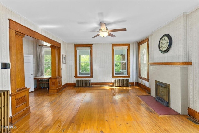 909 Highland Ave, Bristol, VA 24201 - unfurnished living room with radiator heating unit, hardwood / wood-style flooring, a ceiling fan, a fireplace with flush hearth, and wallpapered walls