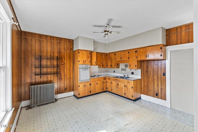 909 Highland Ave, Bristol, VA 24201 - kitchen with radiator, white appliances, ceiling fan, brown cabinetry, and wooden walls