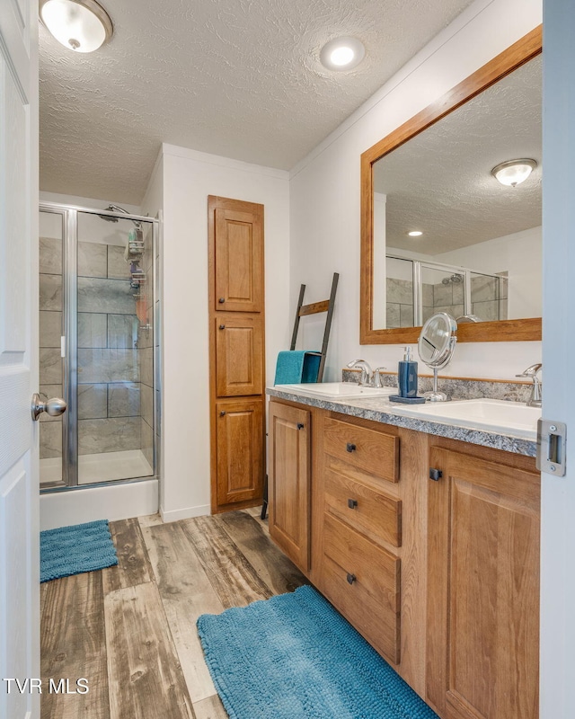 715 Dunham Rd, Chuckey, TN 37641 - full bathroom featuring a textured ceiling, wood finished floors, a shower stall, and double vanity