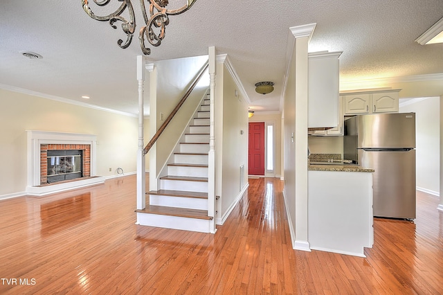 226 Willowbend Ct, Kingsport, TN 37660 - stairs featuring hardwood / wood-style floors, a brick fireplace, crown molding, and a chandelier