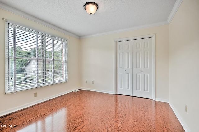 226 Willowbend Ct, Kingsport, TN 37660 - unfurnished bedroom featuring wood finished floors, a textured ceiling, multiple windows, crown molding, and a closet