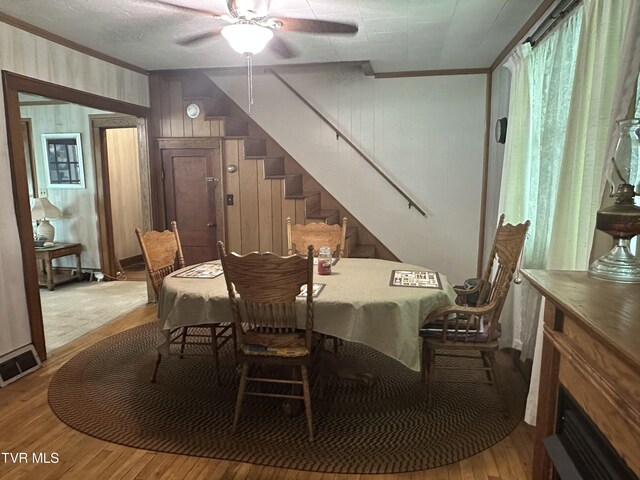 2065 Coeburn Rd, Clintwood, VA 24228 - dining space with wood finished floors, crown molding, a ceiling fan, stairs, and wooden walls