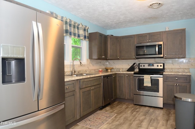 2165 Steadman St, Kingsport, TN 37664 - kitchen with appliances with stainless steel finishes, light countertops, a textured ceiling, tasteful backsplash, and light wood-type flooring