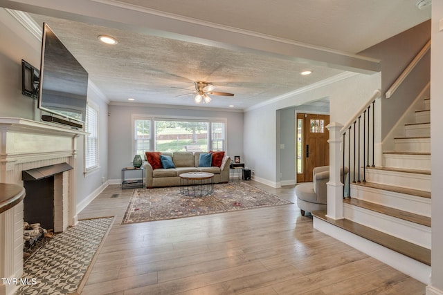 1121 Watauga St, Kingsport, TN 37660 - living room with stairway, a ceiling fan, a fireplace, light wood finished floors, and crown molding