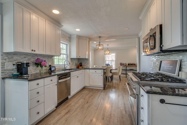 1121 Watauga St, Kingsport, TN 37660 - kitchen with appliances with stainless steel finishes, a peninsula, light wood finished floors, white cabinetry, and backsplash