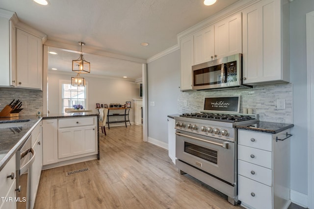 1121 Watauga St, Kingsport, TN 37660 - kitchen with appliances with stainless steel finishes, ornamental molding, white cabinets, decorative backsplash, and light wood-style flooring