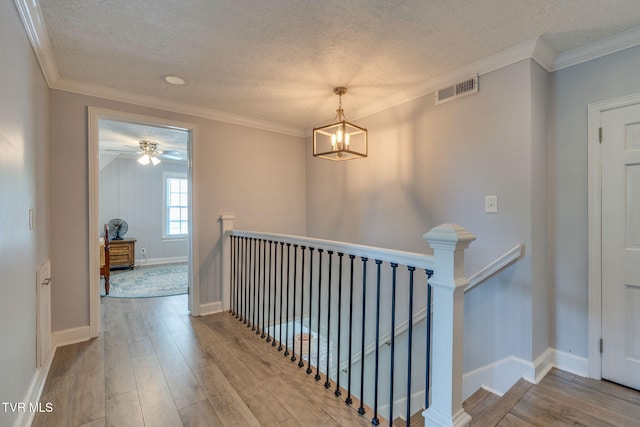 1121 Watauga St, Kingsport, TN 37660 - hall featuring an upstairs landing, wood finished floors, a textured ceiling, a chandelier, and crown molding