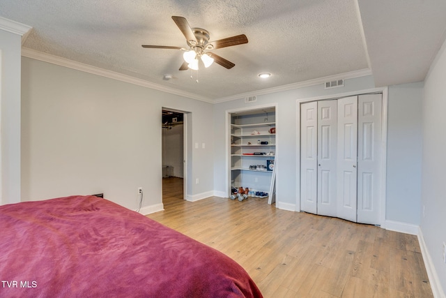 1121 Watauga St, Kingsport, TN 37660 - bedroom featuring a textured ceiling, light wood-style floors, crown molding, a ceiling fan, and two closets
