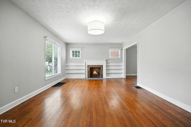 1340 Wateree St, Kingsport, TN 37660 - unfurnished living room featuring a brick fireplace, wood finished floors, and a textured ceiling