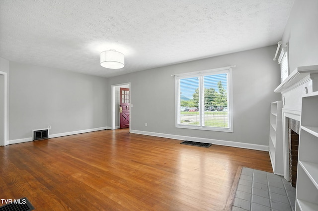 1340 Wateree St, Kingsport, TN 37660 - unfurnished living room with wood finished floors, a fireplace, and a textured ceiling