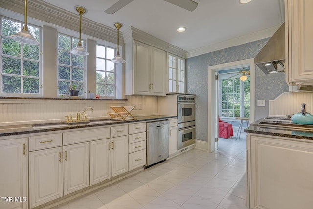 1261 Watauga St, Kingsport, TN 37660 - kitchen featuring ceiling fan, appliances with stainless steel finishes, wallpapered walls, wall chimney range hood, and healthy amount of natural light