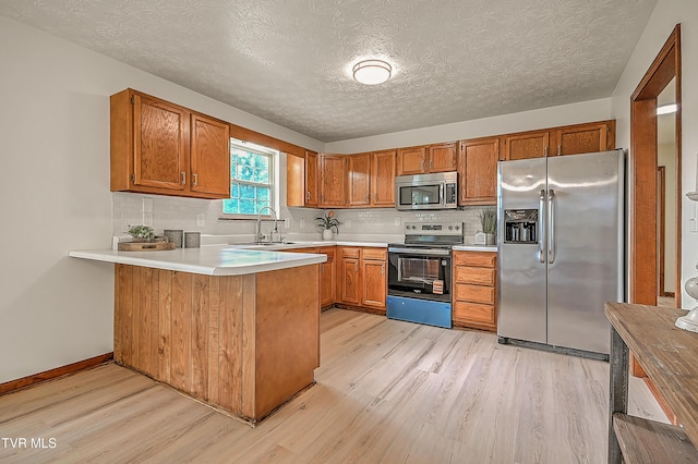 4970 Old Stage Rd, Chuckey, TN 37641 - kitchen featuring stainless steel appliances, light wood-style flooring, a peninsula, brown cabinets, and a textured ceiling