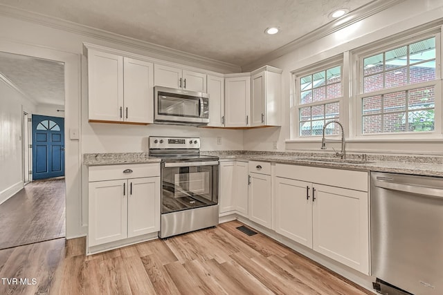 810 N Roan St, Elizabethton, TN 37643 - kitchen with stainless steel appliances, ornamental molding, white cabinets, light wood-style flooring, and light stone countertops