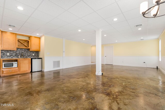 2003 Hackberry Dr, Jonesborough, TN 37659 - unfurnished living room with finished concrete flooring, bar with sink, a wainscoted wall, a paneled ceiling, and ornate columns