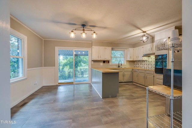 3513 Crest Rd, Kingsport, TN 37664 - kitchen featuring under cabinet range hood, a peninsula, light countertops, crown molding, and oven