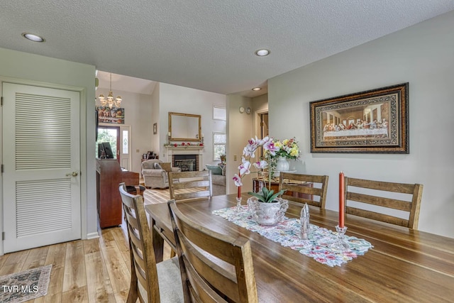 223 Willowbend Ct, Kingsport, TN 37660 - dining space with light wood-type flooring, a chandelier, a textured ceiling, a fireplace, and recessed lighting