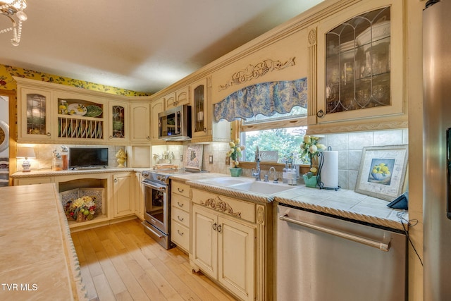 284 Bulldog Holw, Elizabethton, TN 37643 - kitchen featuring appliances with stainless steel finishes, cream cabinetry, backsplash, light wood-style floors, and glass insert cabinets