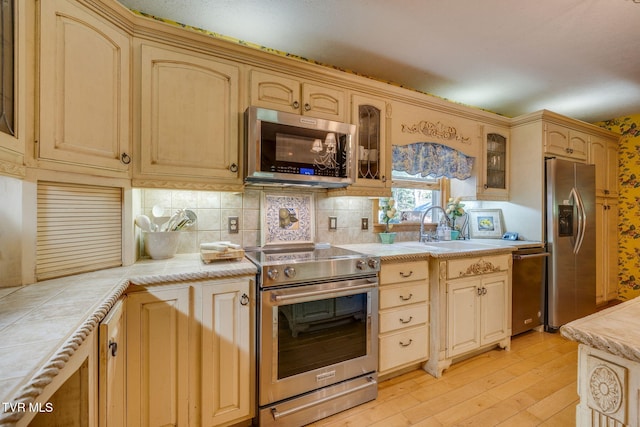 284 Bulldog Holw, Elizabethton, TN 37643 - kitchen featuring stainless steel appliances, light wood-style flooring, glass insert cabinets, and tasteful backsplash