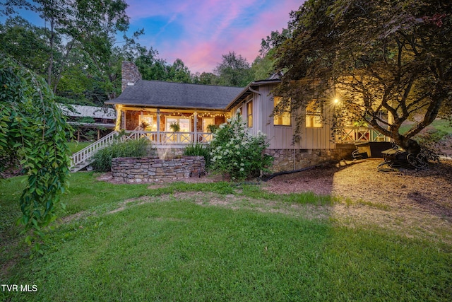 284 Bulldog Holw, Elizabethton, TN 37643 - back of house at dusk with a chimney, board and batten siding, stairs, and a yard